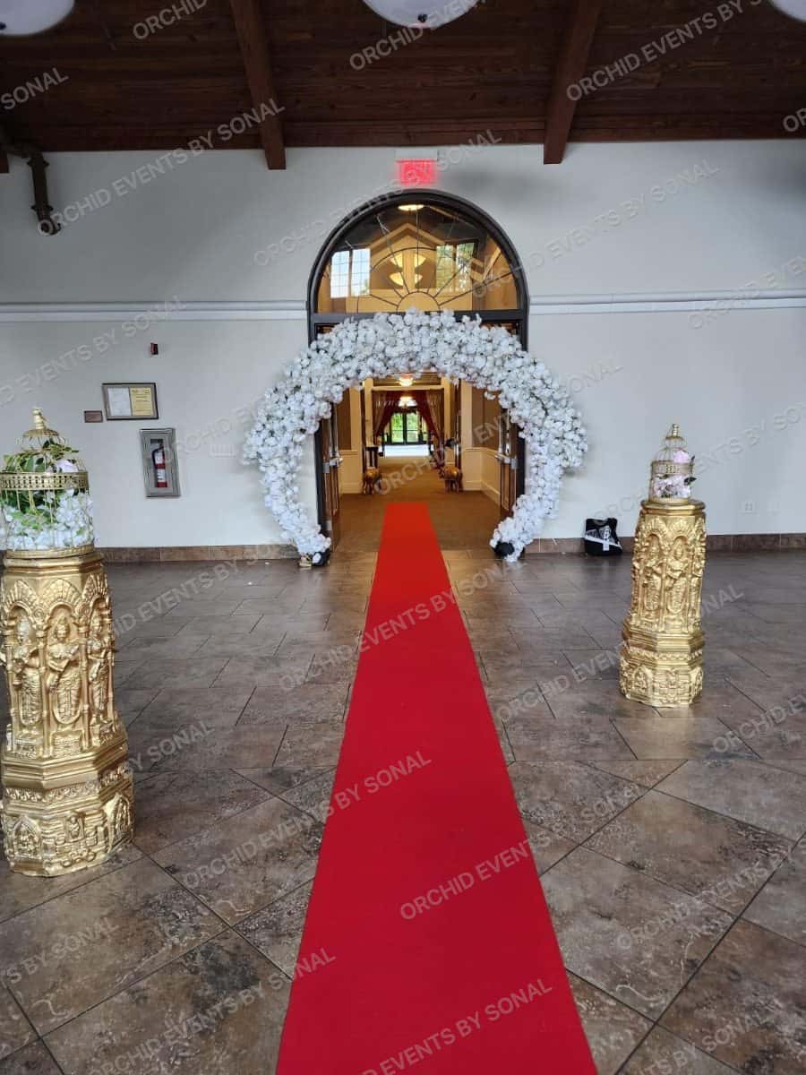 Red carpet running the length of a hall to a white blossom entrance arch