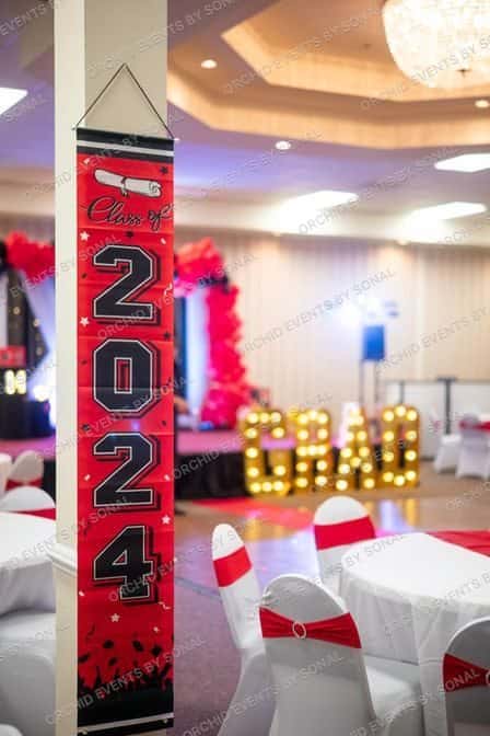 Class of 2024 banner in a banquet hall set with red sashes and lit letters