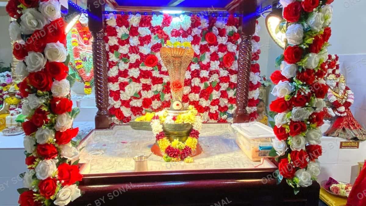 Small puja mandap banked in red and white roses around a lit shrine