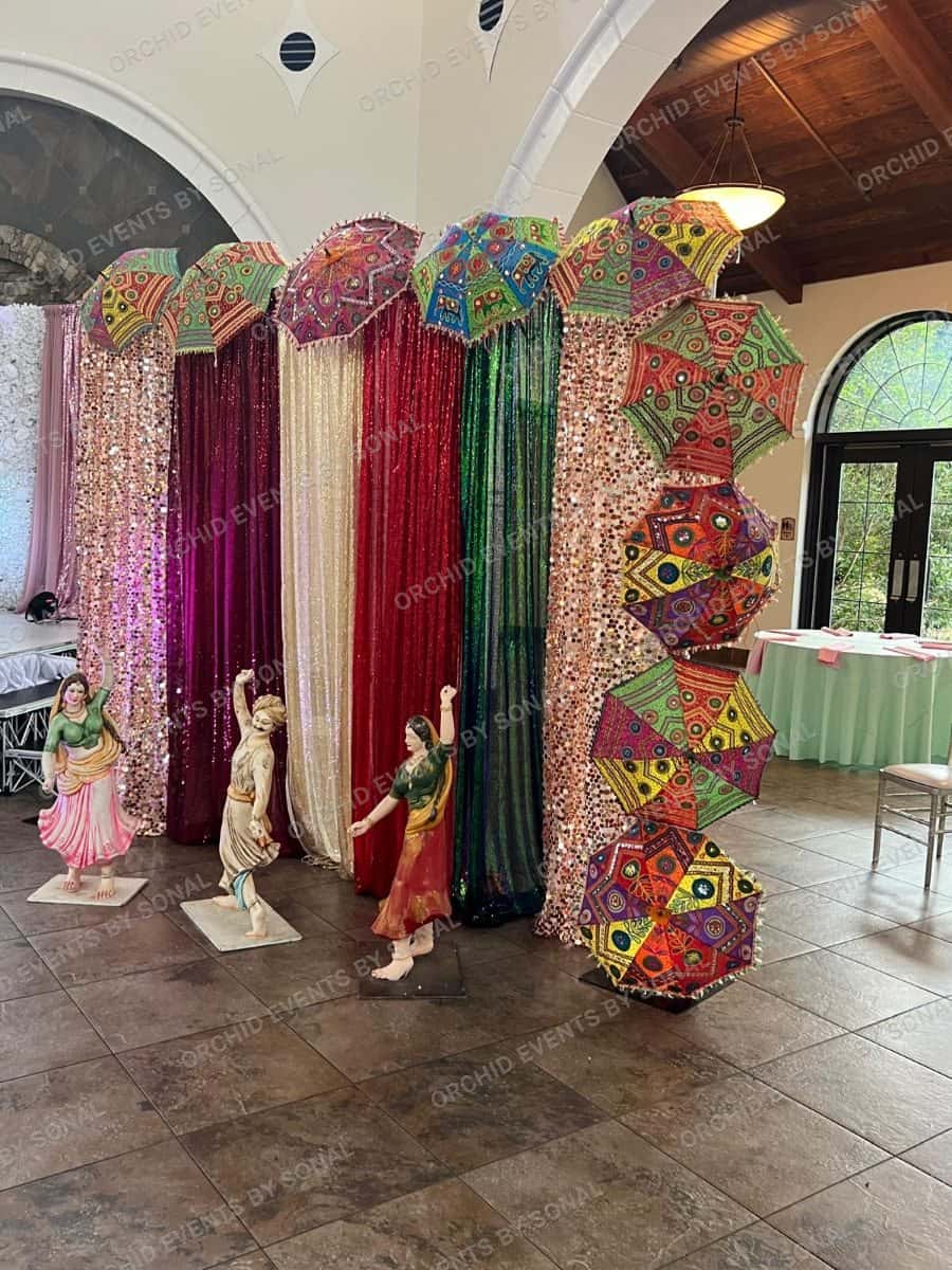 Sequin curtain backdrop with mirrored umbrellas and painted folk statues