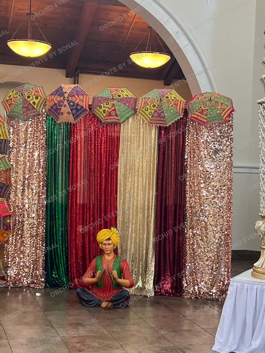 Wall of sequin curtains in jewel tones topped with embroidered umbrellas